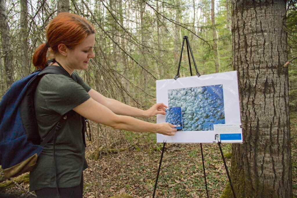 Photo: Woman holding photo of water droplets up to picture it was made from