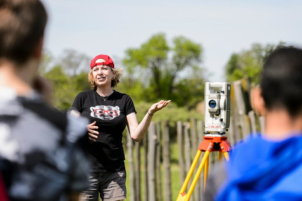 Photo: Schroeder gesturing toward a survey camera on a tripod