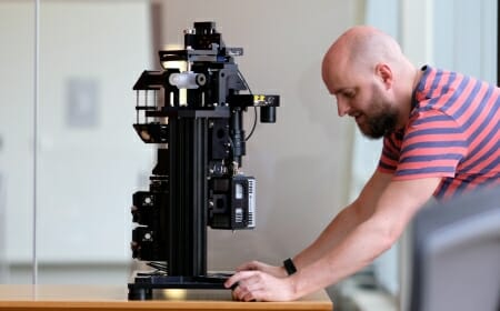 Photo: Researcher looking at microscope on lab bench