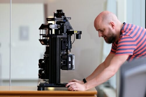 Photo: Researcher looking at microscope on lab bench