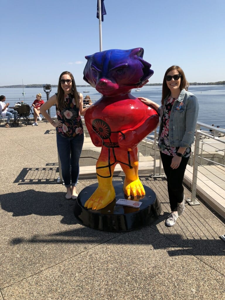 Allyson Casey and Megan Breene stand next to Sunset Bucky, one of 85 unique Bucky Badger statues designed for Bucky on Parade, a public art project.