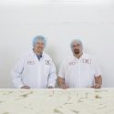 Matt Erdley and Ron Buholzer, the newest master cheesemakers, stand in front of the brine tank holding muenster cheese during processing.
