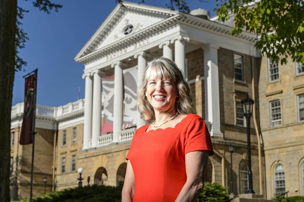 Photo: Lori Reesor standing in front of Bascom Hall pillars with Bucky Banner