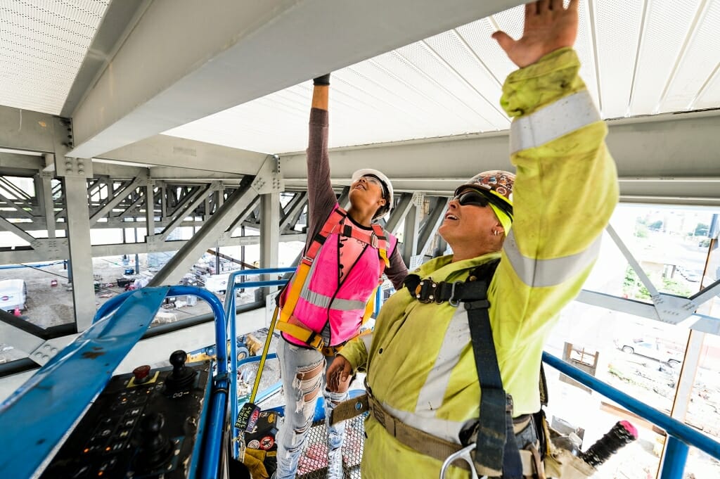 Riding in a bucket lift, ironworker Jesse McKnight, at right, surprises Jamiah Jones, 14, with the chance to touch a ceiling beam more than 60 feet above the ground.