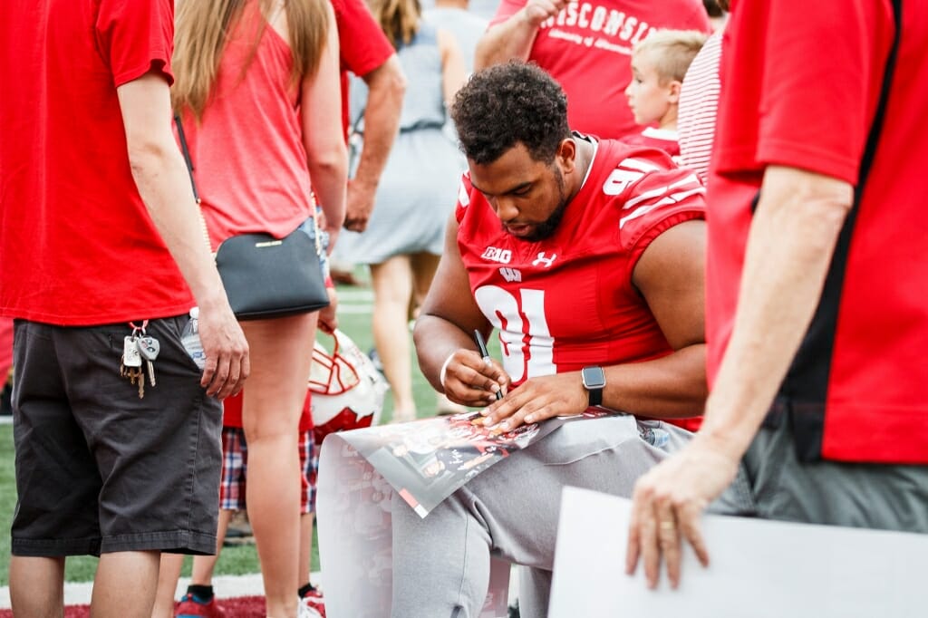 Wisconsin nose tackle Bryson Williams (91) autographs a fan's poster.