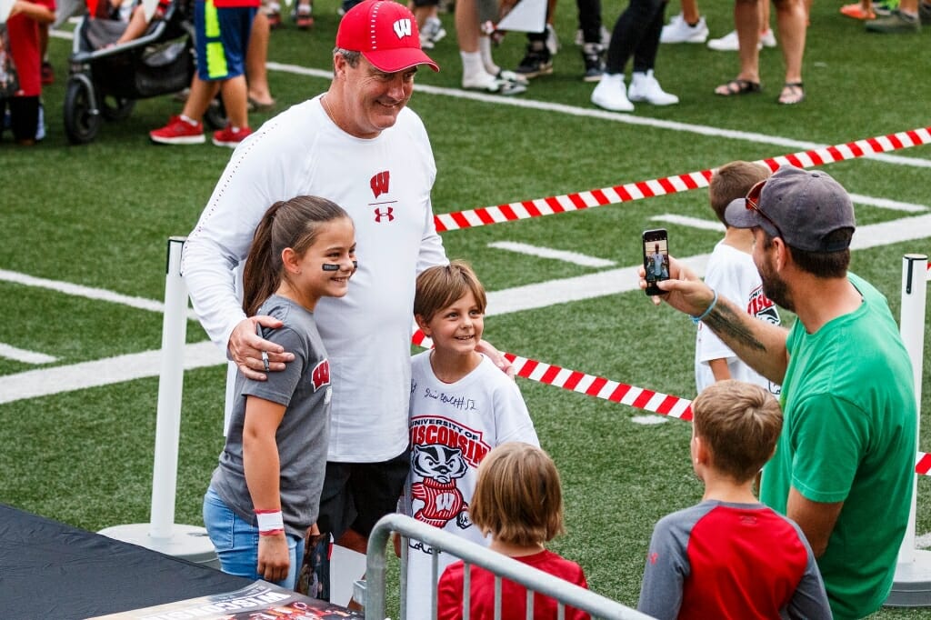 Head football coach Paul Chryst 
poses for a picture with young fans.