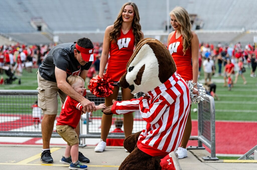 Bucky Badger and two cheerleaders welcome a young fan.