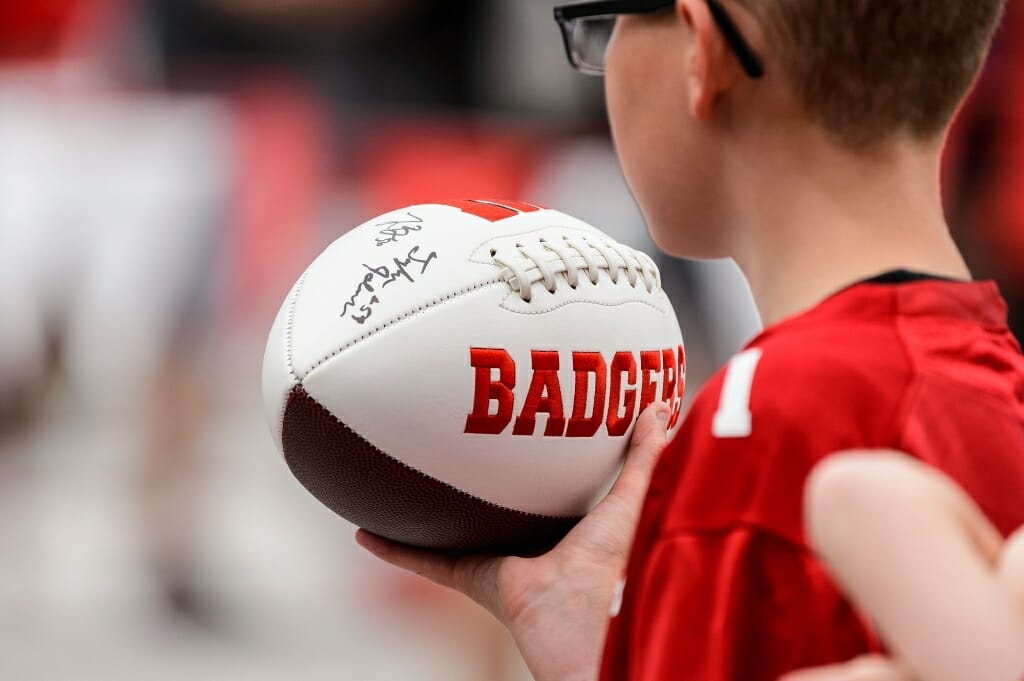 A young fan carries an autographed football.