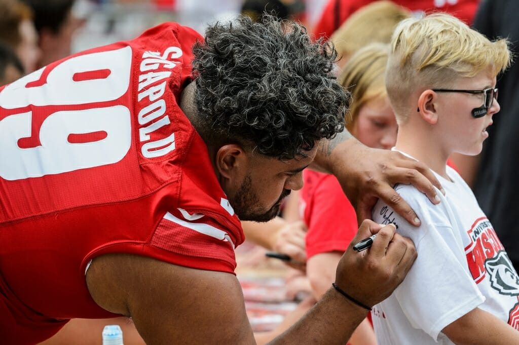 Wisconsin nose tackle Olive Sagapolu (99) signs a fan's shirt.