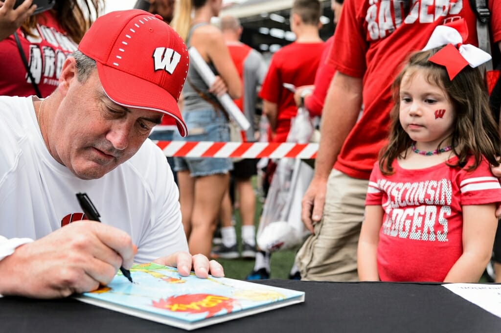 Football coach Paul Chryst signs Amia Riddle-Corey's book, The Lorax.