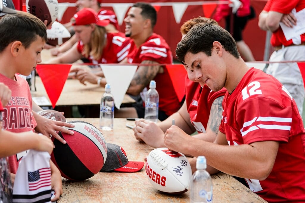 A young fan looks on as Wisconsin quarterback Alex Hornibrook (12) signs a football.