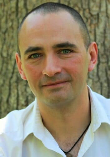 Photo: Closeup of Jean-Michel Ané in front of a tree trunk
