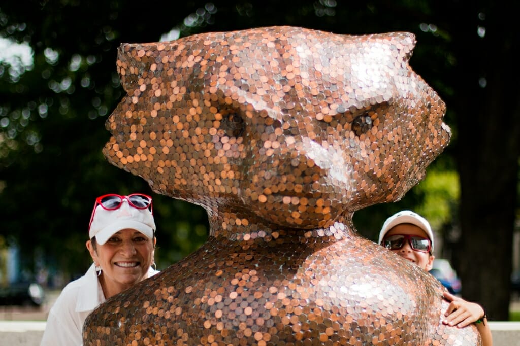 A child and his grandmother pose by a Bucky statue decorated with pennies.