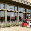 Photo: Student pushing red laundry cart in front of large building windows