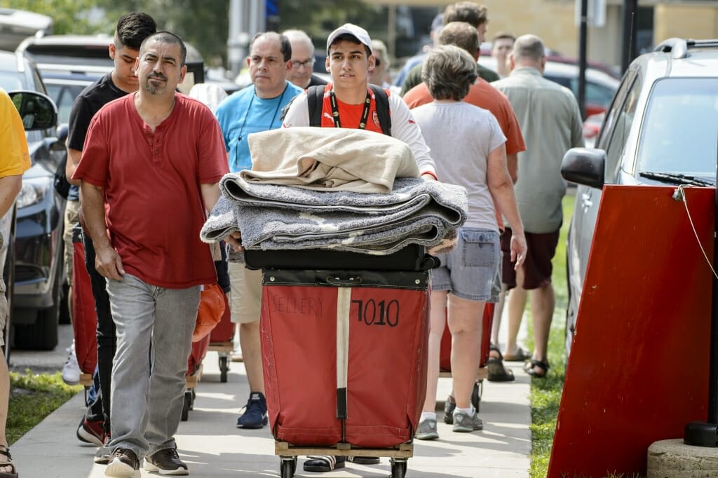 Photo: Student pushing red laundry cart overflowing with things