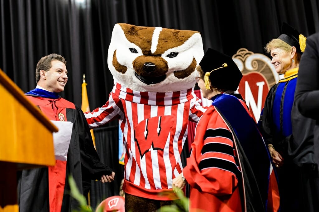 From left to right, undergraduate student speaker Yogev Ben-Yitschak, Chancellor Rebecca Blank, and Provost Sarah Mangelsdorf welcome UW-Madison mascot Bucky Badger to the stage at the end of the ceremony.