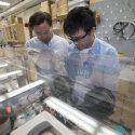 Photo of Song Jin, left, and graduate student Wenjie Li observing their lab-scale device for storing and releasing solar energy.