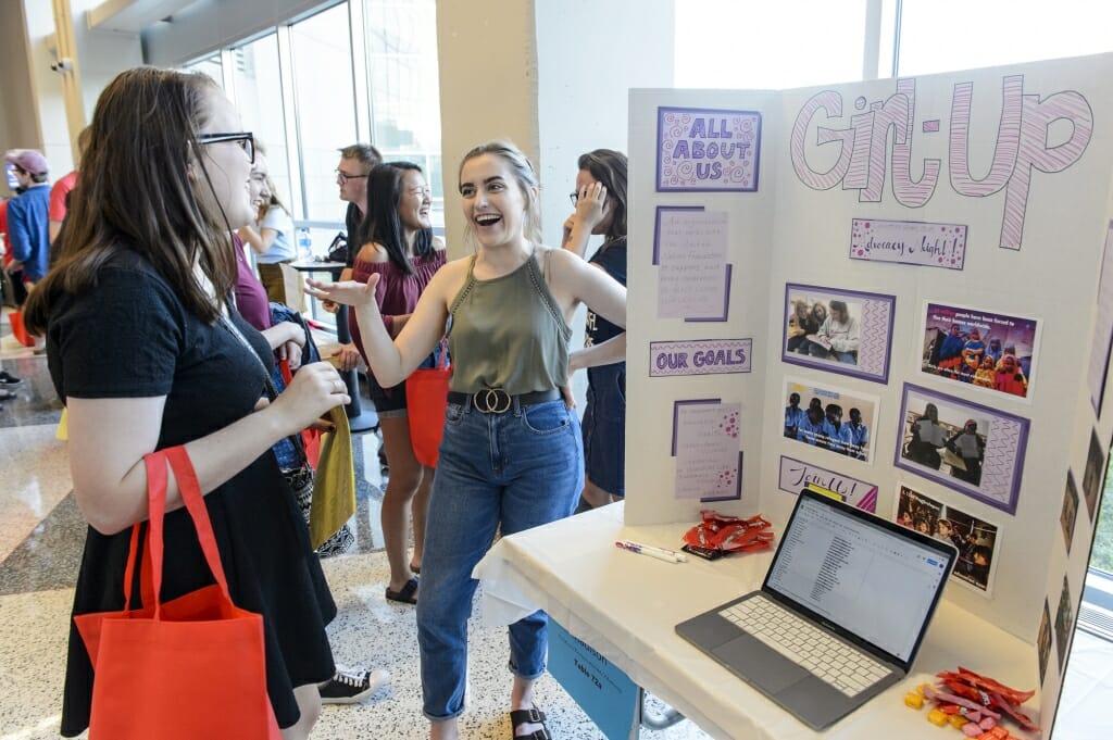 Catherine Torner (right) talks to a student at the Girl Up booth.