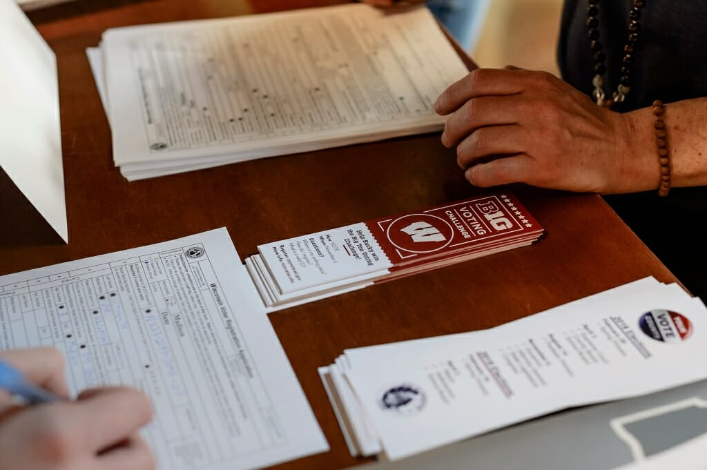 Voter registrations forms are filled out at a table.