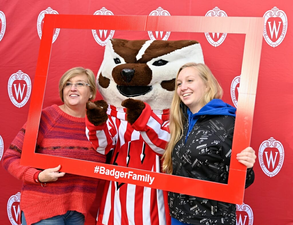 Mother and daughter pose with Bucky Badger in a frame.