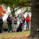 Patty Loew (wearing white sweater vest at center), professor of life sciences communication and a Bad River tribal member, talks about cultural history and digital storytelling with nine high school students from Wisconsin's Ho-Chunk Nation as the youth gathered near a Native American effigy mound and the Tree of Peace on Observatory Hill at the University of Wisconsin-Madison during autumn on Oct. 23, 2015. The UW Arboretum's Earth Partnership Program and UW-Madison's Nelson Institute for Environmental Studies hosted the group's one-day visit to campus. (Photo by Jeff Miller/UW-Madison)