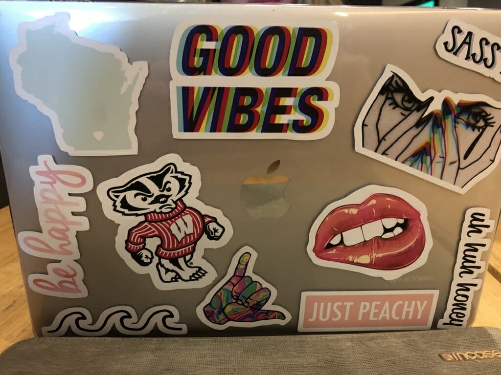 Sophomore Ellery Gronski's laptop, which features a "Good Vibes" sticker, a few referencing Madison and UW, a sticker of red lipstick-ed lips, and one that says "Just Peachy," among others. 