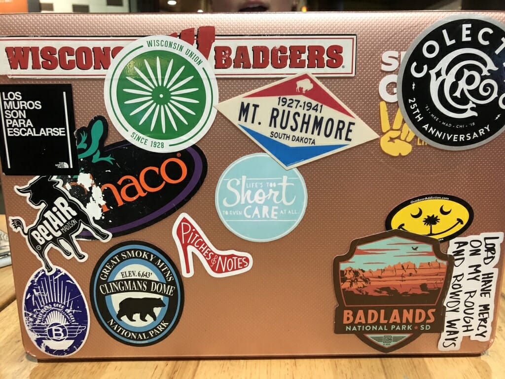 Junior Jessa Hansen's laptop which features a few coffee shop stickers, one from mt. rushmore and the Badlands, a Wisconsin Union chair sticker, and song lyric. 