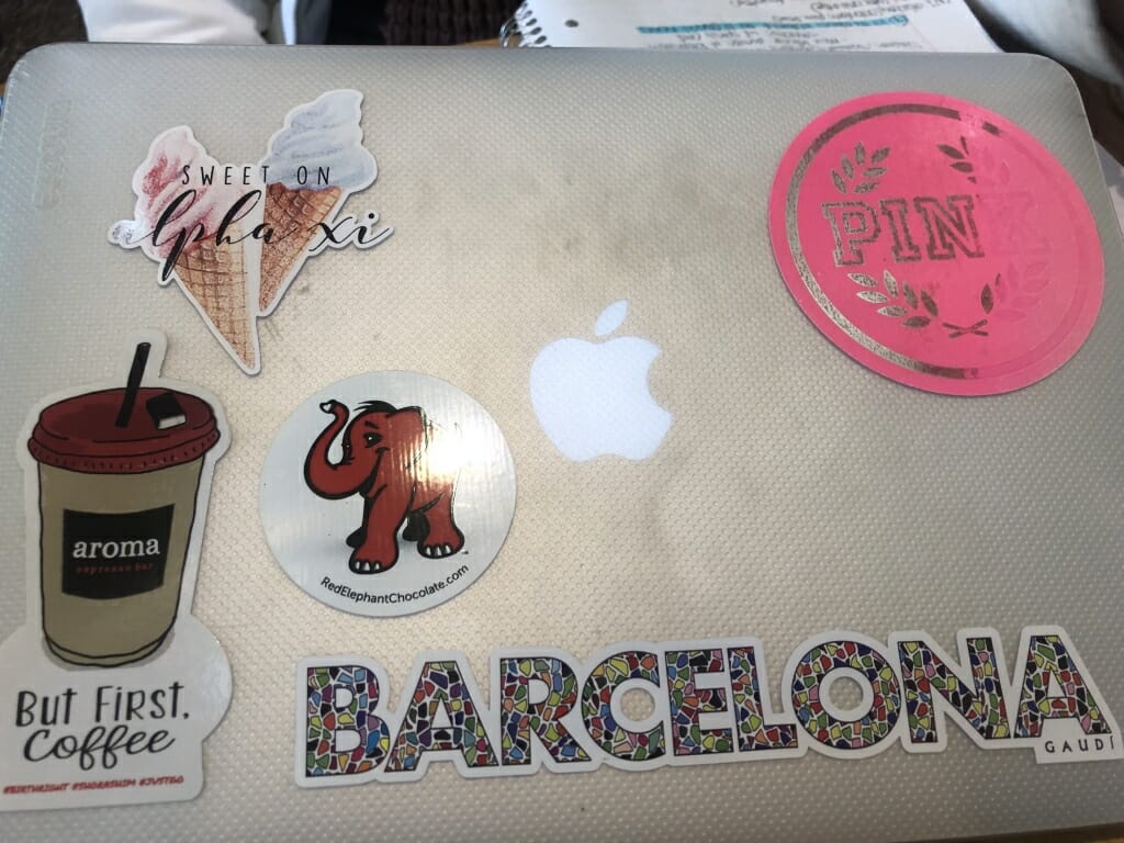 Sophomore Autumn Facktor's laptop, which features a Barcelona sticker, one of an Elephant, a Victoria Secret "Pink" logo sticker, and one of Alpha Xi sorority. 