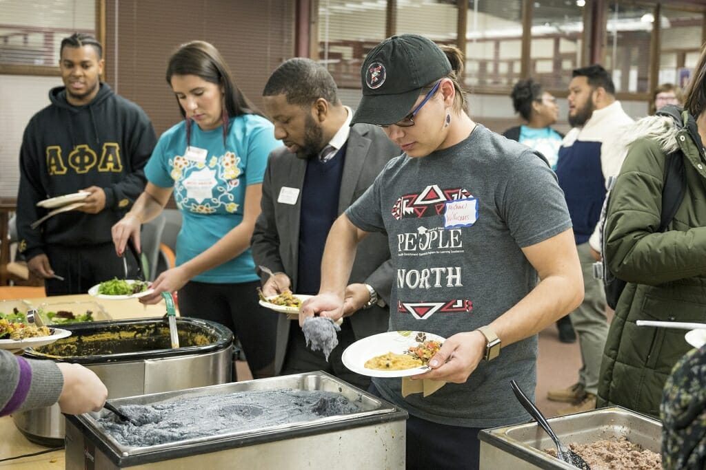 A line of students work their way down the food table, filling their plates.