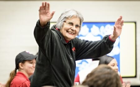 Ada Deer raises her hands in greeting to the students.