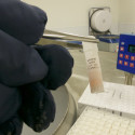 Photo: Gloved hand holding vial with tweezers