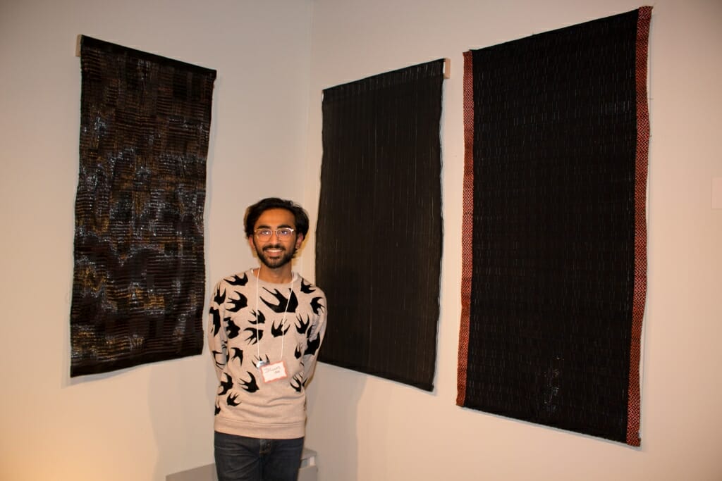 Photo: A man with some wall hangings he designed.