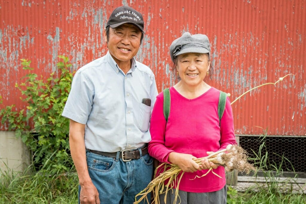 Photo: A man and a woman pose in front of a barn.