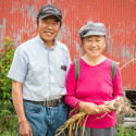 Photo: A man and a woman pose in front of a barn.