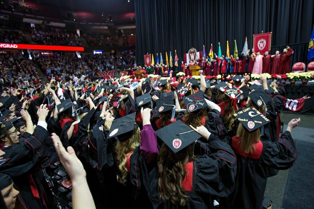 Photo: Graduates wearing robes listen to the ceremony during commencement.