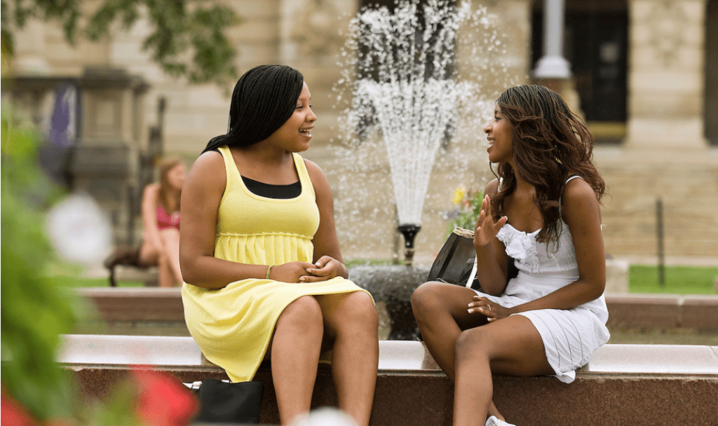 Students Bettina Billings (left) and Tessia Brown (right) spend a moment talking at the fountain on Library Mall.