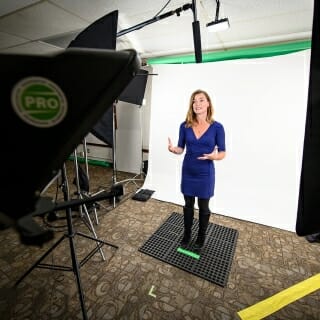 Photo: Sara McKinnon standing in front of a white screen before a video camera