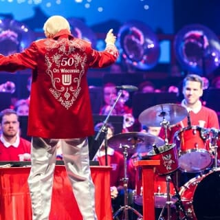 Photo: Mike Leckrone conducts in a red jacket embroidered with "50"