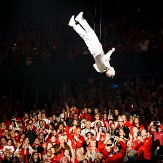 Suspended on a wired harness, the 82-year-old Leckrone performs flips above the audience.