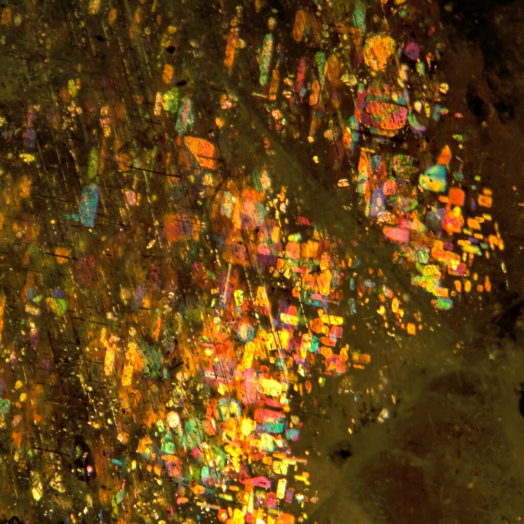 Photo: the rainbow of colors reflected by microscopic flakes of hematite trapped in a dark crystal of labradorite feldspar