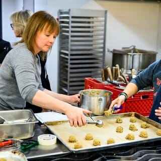 Photo: Two women scoop cookie dough onto a cookie sheet.