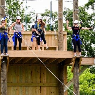 Photo: People wearing helmets stand on a ropes course platform.