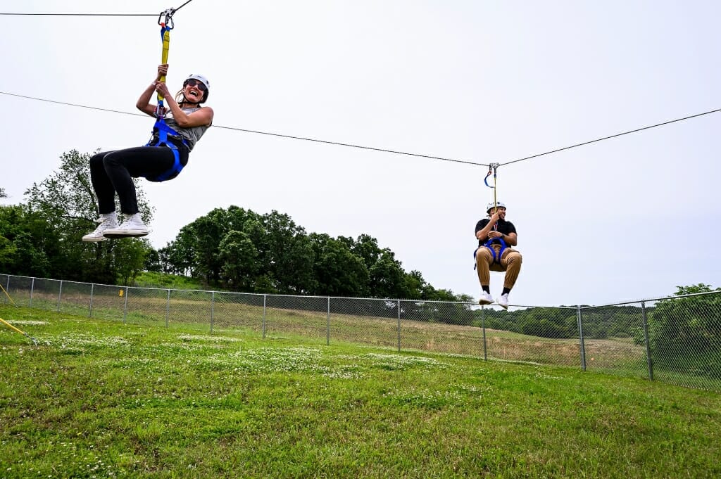Photo: Two people ride along a zipline.