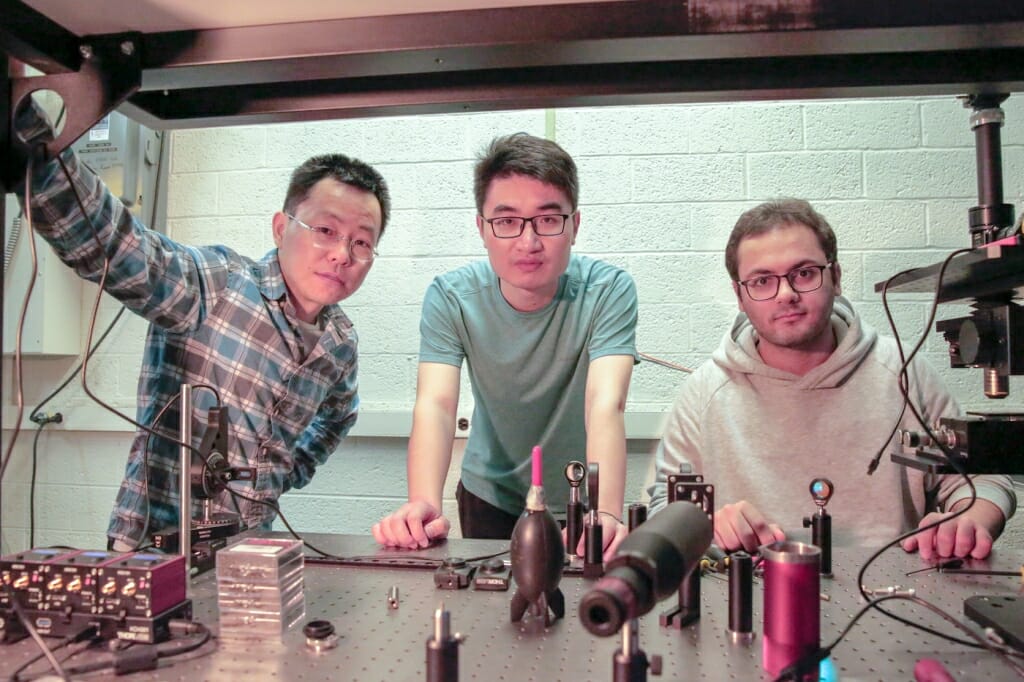 Photo: Three researchers gather in a lab.