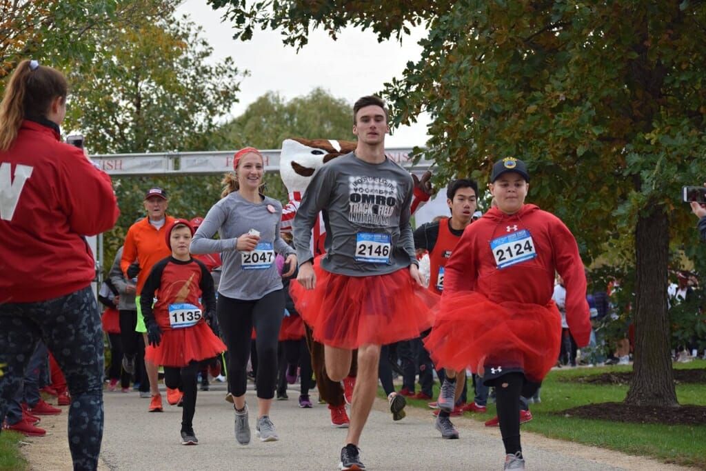 Photo: Students wearing athletic clothes and red tutus run.