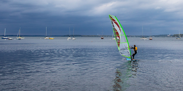 Photo: Windsurfer on the water under gathering dark clouds