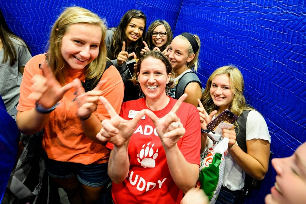 Photo of Dean of Students Christina Olstad flashing the W with new students in a Witte Residence Hall elevator.