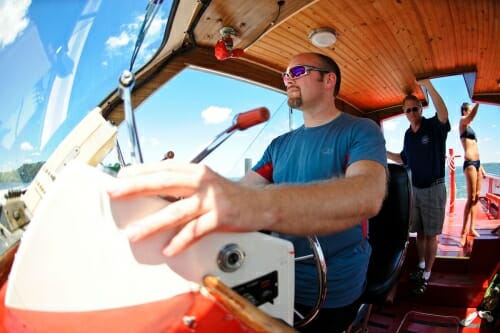 Photo: Man at the wheel of a boat with 2 other people standing