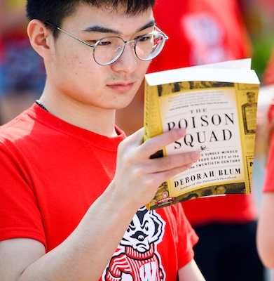 Photo: Student holding book and looking at the back cover