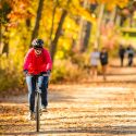 Photo: Bicyclist riding on path through trees with fall colors